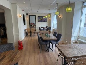a restaurant with wooden tables and chairs and a room with windows at Arcades Hôtel - Cholet in Cholet