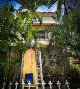 a sign in front of a building with palm trees at Canario Boutique Hotel in San Juan