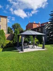 a gazebo with chairs and tables on a lawn at Linda Hotel in Liepāja