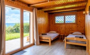 two beds in a wooden room with a window at Chalet SOL LA MI in Soultzeren