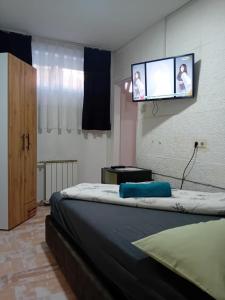 Un dormitorio con una cama con un televisor de pantalla plana en la pared. en EM Apartments Korzo, en Tuzla