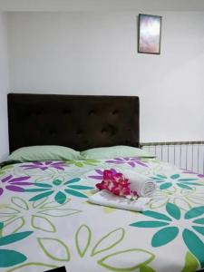 Una cama con un edredón de flores. en EM Apartments Korzo, en Tuzla