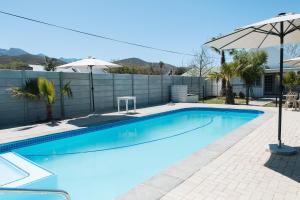 a swimming pool with an umbrella next to a fence at Old Posthouse Guest Accommodation in Ladismith