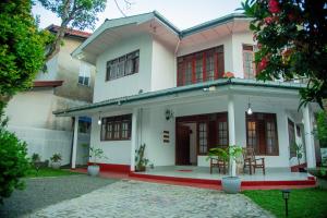 ein weißes Haus mit roten Fenstern und einer Terrasse in der Unterkunft Cottage Haven Villa in Galle
