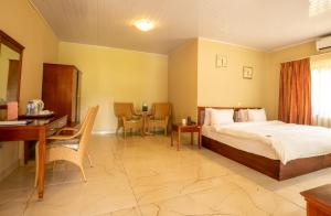 a bedroom with a bed and a desk and a table at Busua Beach Resort in Busua