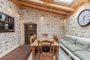 a dining room with a table and a couch and a clock at Sponza House in Trstenik