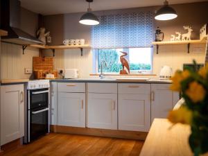a kitchen with white cabinets and a window at 1 Bed in Horningtoft 91344 in Whissonsett