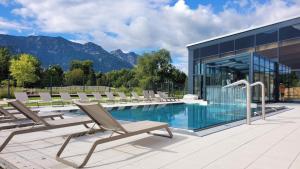 a pool with lounge chairs next to a building at Hardi's Hotel in Inzell