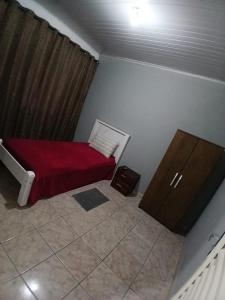 a small bedroom with a red bed and a cabinet at Pousada conti viracopos in Campinas