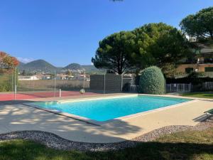 a swimming pool in a yard with a tennis court at Duplex provençal au cœur des vignes à 5 min du centre-ville in Sablet