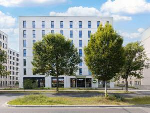 a white building with two trees in front of it at B&B HOTEL Berlin Airport-Nord in Berlin