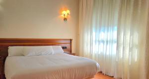 ein Schlafzimmer mit einem großen weißen Bett und einem Fenster in der Unterkunft Hotel Las Moreras in León