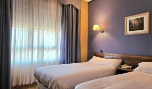 a hotel room with two beds and a window at Hotel Las Moreras in León