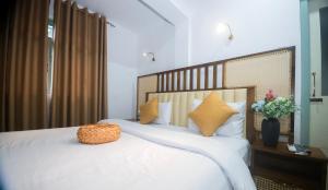 a bedroom with a bed with white sheets and yellow pillows at The Living Villa in Badulla