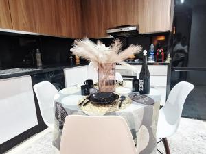 a table with white chairs and a vase with feathers at Appartement Le Guéliz,au centre de Marrakech, pool & fast WiFi in Marrakech