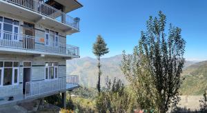 a building with a view of the mountains at Sunrise View Farm-stay -Narkanda in Shimla