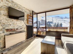 a living room with a stone wall with a tv at Résidence Lac du Lou - Les Ménuires in Les Menuires