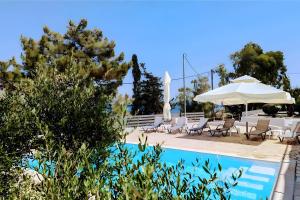 a pool with chairs and a table and an umbrella at Euphoria Apartments in Kouvaláta