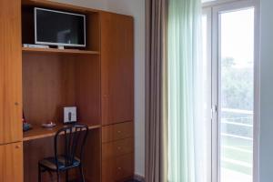 a room with a tv and a chair and a window at Hotel Villa Maria in Crispiano
