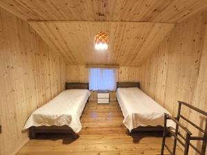 Hostel Cozy House في Sioni: سريرين في غرفة خشبية مع نافذة
