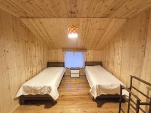 2 letti in una camera in legno con finestra di Hostel Cozy House a Sioni