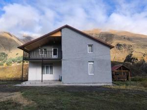 una casa en una colina con montañas al fondo en Hostel Cozy House, en Sioni