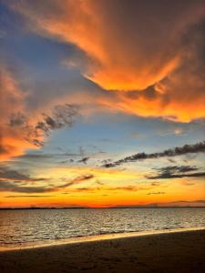 una puesta de sol sobre el océano con una playa de arena en Hostería Amar, 