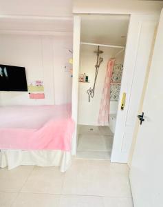 a bedroom with a pink bed and a tv at Habitación con baño y cocina in Caudiel +1 photo