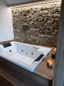 a white bath tub in a bathroom with a stone wall at Conte Luxury Rooms in Salerno