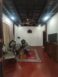 Traditional 4 Bedroom Villa - Sukun Heritage في كانور: غرفة معيشة مع كراسي وتلفزيون وسجادة