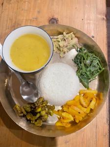 a plate of food with a bowl of soup and vegetables at Walk in the Himalayas in Pelling