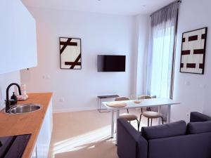 une cuisine et un salon avec une table et un canapé dans l'établissement TAYP Navalmoral Apartamentos, à Navalmoral de la Mata