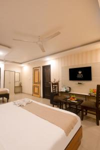 a bedroom with a bed and a table and a tv at Hotel Krone Delhi in New Delhi