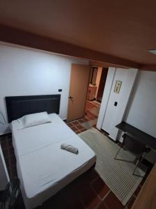 a bedroom with a white bed and a desk at Hostal Casa Primavera in Medellín +14 photos