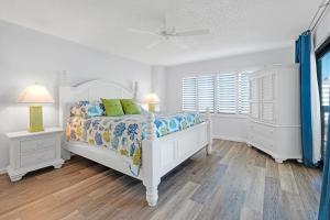 a white bedroom with a bed and two night stands at Oceanfront with great beach views from all rooms & balcony, heated pool, and garage in Ormond-by-the-Sea +34 photos