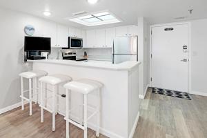 a kitchen with white cabinets and a counter with stools at Oceanfront with great beach views from all rooms & balcony, heated pool, and garage in Ormond-by-the-Sea