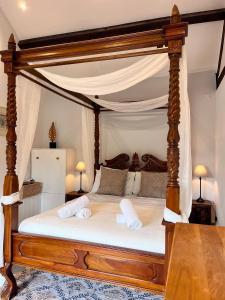a bedroom with a canopy bed with two towels at Stable Cottage, Oxfordshire in Oxford