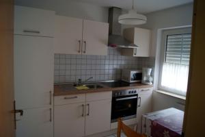 a small kitchen with white cabinets and a sink at Thesing RE22 in Sögel