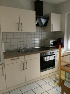 a kitchen with white cabinets and a sink and a stove at Thesing RE22 in Sögel