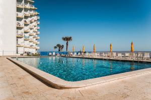 a swimming pool next to a building and the ocean at New listing! Direct oceanfront condo with a balcony, heated pool, and tennis court in Bottle Island