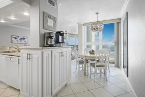 a kitchen with white cabinets and a table with chairs at New listing! Direct oceanfront condo with a balcony, heated pool, and tennis court in Bottle Island