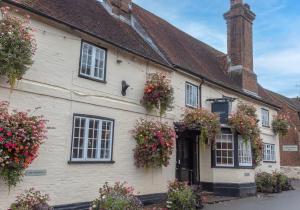 an old white building with flowers on it at The Kings Head in Whiteparish