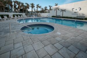 a large swimming pool with chairs and a building at New listing! Direct oceanfront with private balcony, pool, and hot tub in Bottle Island