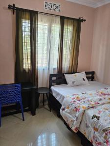 a bedroom with two beds and a chair and a window at Nestova Hostel in Nkunjila