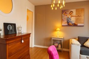 a living room with a couch and a pink chair at L'ancienne Trésorie Mâconnaise Parking - 6 people in Mâcon