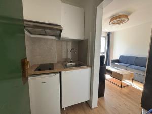 Una cocina con fregadero y un sofá en una habitación. en New Apartment Hotel Palais des Congrès Porte Maillot 31, en Levallois-Perret