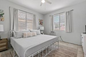 a bed in a bedroom with white walls and windows at Town Treasure - Walkable - King Bed - AC in Christiansted