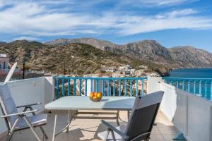 Una mesa y sillas en un balcón con vista al mar. en Hotel Glaros Karpathos, en Diafani