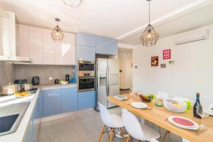 een keuken met blauwe kasten en een houten tafel met stoelen bij Villa Florentina by Villa Plus in Štokovci