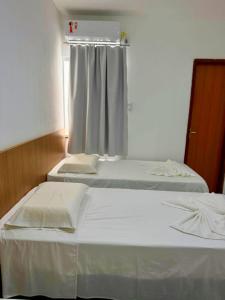 Dos camas individuales en una habitación con ventana. en Hotel Ideal, en Jequié